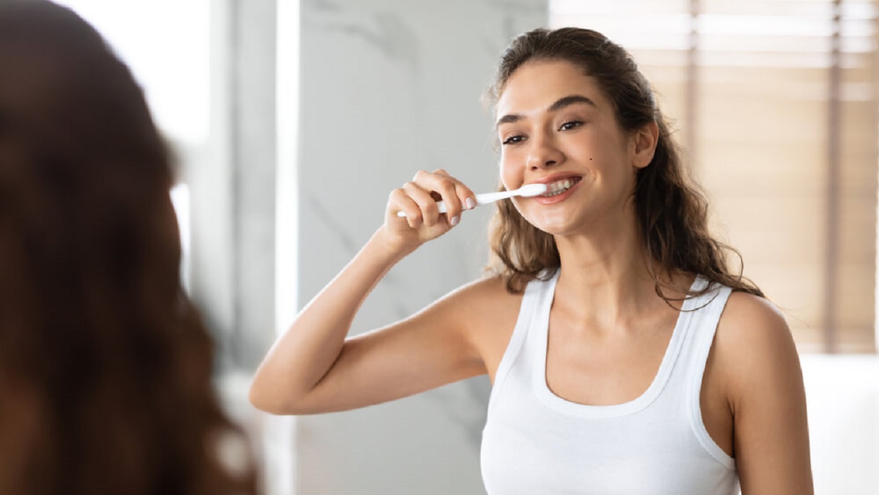 kobieta myjąca zęby przed lustrem